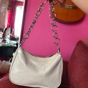 Väska - Väska från Nelly med kedjor, hyfsat stor men läder mönster i beige. Säljer för 100kr frakt ca 50kr. Kan även mötas upp i stockholm.