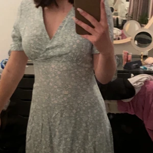 Grön blommig klänning  - Jätte söt och fin klänning, aldrig använd men så fin så hoppas nån annan får användning för den. Mint grön med vita blommor på 