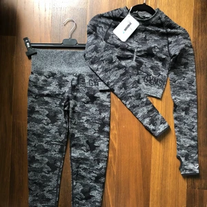 GymShark Grå Camo Set - Komplett träningsset i nyskick beställt från Gymshark. Toppen är helt oanvänd och tightsen har använts 1 gång. Plaggen säljs även separat, för mer detaljer och bilder se respektive annons. Rabbaterat pris vid köp av båda plaggen - 400kr. Annars kostar Toppen (XS) 150kr och Leggingsen (S) 300kr. Kan mötas i Uppsala eller skicka (frakt 62kr + 50kr kostnadstillägg om SafePay önskas). Fler plagg från GymShark i min profil.