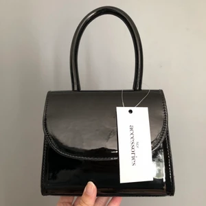 Helt oanvänd mini bag från Nelly - Jättesöt väska från Nelly i färgen ”Black Patent” 💖Köpt för nått år sedan men kom aldrig till användning. Köparen står för frakt!