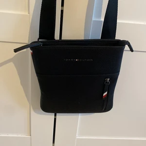 Tommy Hilfiger axelväska  - Säljer denna svarta Tommy Hilfiger axelväska köpt från Tommy hilfiger affären i centrala Stockholm. Säljer pga att jag inte använder den och den är i jättebra skick.