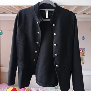 Svart kavaj storlek L  - En svart stilig kavaj med silver knappar. Är gjord av en väldigt elastiskt material.( Kontakta mig för frakt pris).