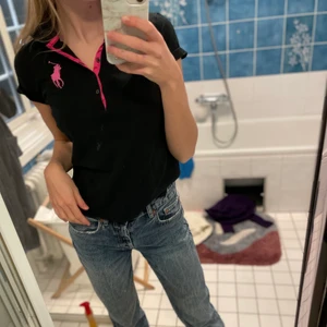 Ralph Lauren Polotröja - Svart&rosa Polotröja/T-shirt från Ralph-Lauren i perfekt skick. Jättefin till våren och sommaren. Den är i största barnstorlek (16) men sitter som en XS/S/M i damstorlek beroende på hur man vill att den ska sitta (jag är 170) 💕💕 