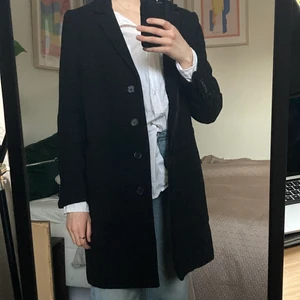 Svart ullkappa - Svart kappa från WERA i 80% ull. Axelvaddar och sköldpaddsfärgade knappar. Knappar i ärmslut och för knäppning i mitten. Lite slitningar baktill på sista bilden, är inte så synliga irl. Strl 40 men upplevs mindre (jag är 36:a för referens). Möts upp i första hand då den är tung och otymplig att posta ✨