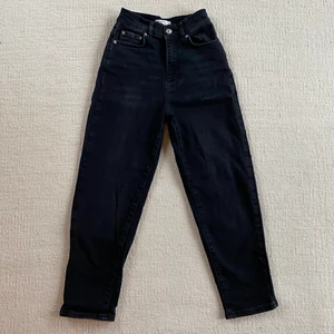 Svarta mom jeans - Svarta mom jeans från gina tricot. Modellen heter comfy petite mom jeans och de är höga i midjan med ankellängd på mig som är 158cm. Knappt använda så det är i väldigt bra skick. Kan mötas upp eller skicka. Köparen står för frakten. 🖤
