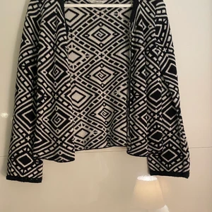 Kofta med utsvänga ärmar  - Säljer min fint mönstrade kofta i vit och svart. Säljer då den ej kommer till användning. Den är utsvängd vid ärmarna och använd ett fåtal gånger. Storleken är 32/34 