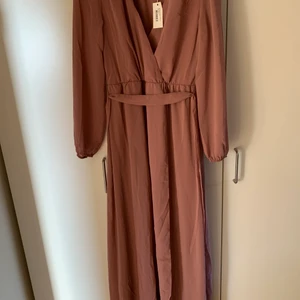 Balklänning i rosa - En rosa balklänning från Nelly. Lösare klänning som man kan knyta i midjan. Storleken är 34 men passar personer med storlek 36 med. Säljer på grund av att jag hittade en annan klänning till min bal. Köparen står för frakten.