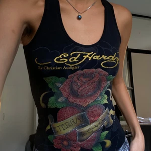 Ed Hardy linne - En svart topp med rhinetones från Ed Hardy. Storlek Small. Inga fläckar eller hål. Några lossnade stenar men inget överdrivet. Se bilder. Skriv vid frågor eller funderingar ☺️