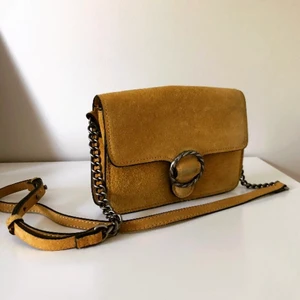 Gul mockaväska - Väska i senapsgul äkta mocka från Mango. Justerbart axelband. Stänga med magnetknapp. Har ficka som går att stänga med dragkedja.