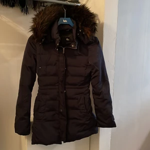 Vinterjacka med fake päls - Marinblå vinterjacka från Zara med brun pälskrake på luvan. Avtagbar luva. Jackan har både dragkedja och knappar. Sitter väldigt fin på och är figursydd. Strl XS. Fin skick!