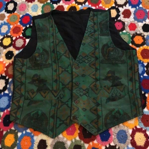 Grön fet väst! - Jävligt fet grön vest i perfekt använt skick! Cowboy och buddha motiv, vilket e jävligt snyggt. Sitter som M-L men mer som en M(: Snyggt som fan under en jacka eller utan! Möts i Malmö och tar Swish. Står ej för frakt eller postens slarv (: