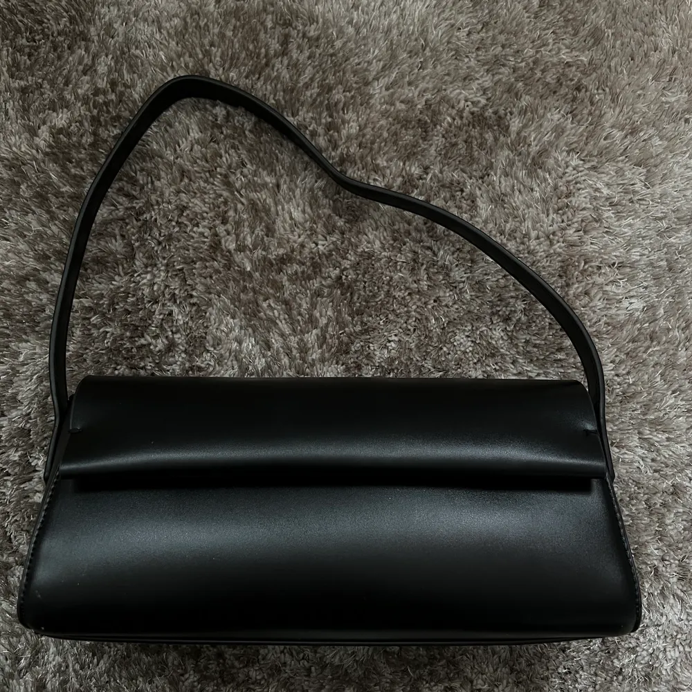 Säljer en jättefin svart liten väska från na-kd, som tyvärr inte kommer till användning längre och vill därför hitta ett nytt hem. Väskan har en liten ficka med dragkedja inuti. . Väskor.