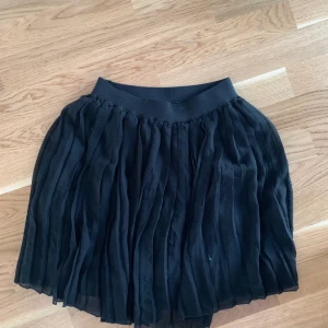 Kort plisserad svart kjol - Knappt använd, Strl S