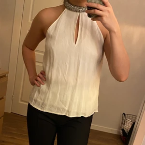 Festlinne från Gina tricot - Snyggt vitt linne med glittrig krage i halsen. Använd en gång och i gott skick. Liten i storleken, linnet är i strl 42 och motsvarar medium. 