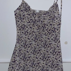 Fin blommig sommarklänning  - En superfin oanvänd blommig sommarklänning i storlek L men passar mer s-m den är ungefär med tills mitten på låren och har en lång dragkedja i ryggen