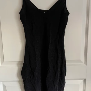 Svart tight klänning - En svart tight glitterklänning. Passar perfekt för fest eller roligare dagar! Klänningen var köpt att använda på nyår med blev en annan klänning istället. Tyget är något tunnare i vissa ljus 