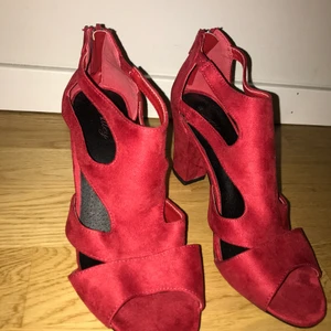 Röda klackskor  - Oanvända röda klackskor med låg klack. Halvt öppna med dragkedja bak. Inte kommit till användning. Storlek 38. 