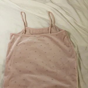 Ett rosa linne med stjärnor på. - Ett rosa linne med stjärnor på och späts där uppe med en roset i mitten där uppe. Matrial samut.💗