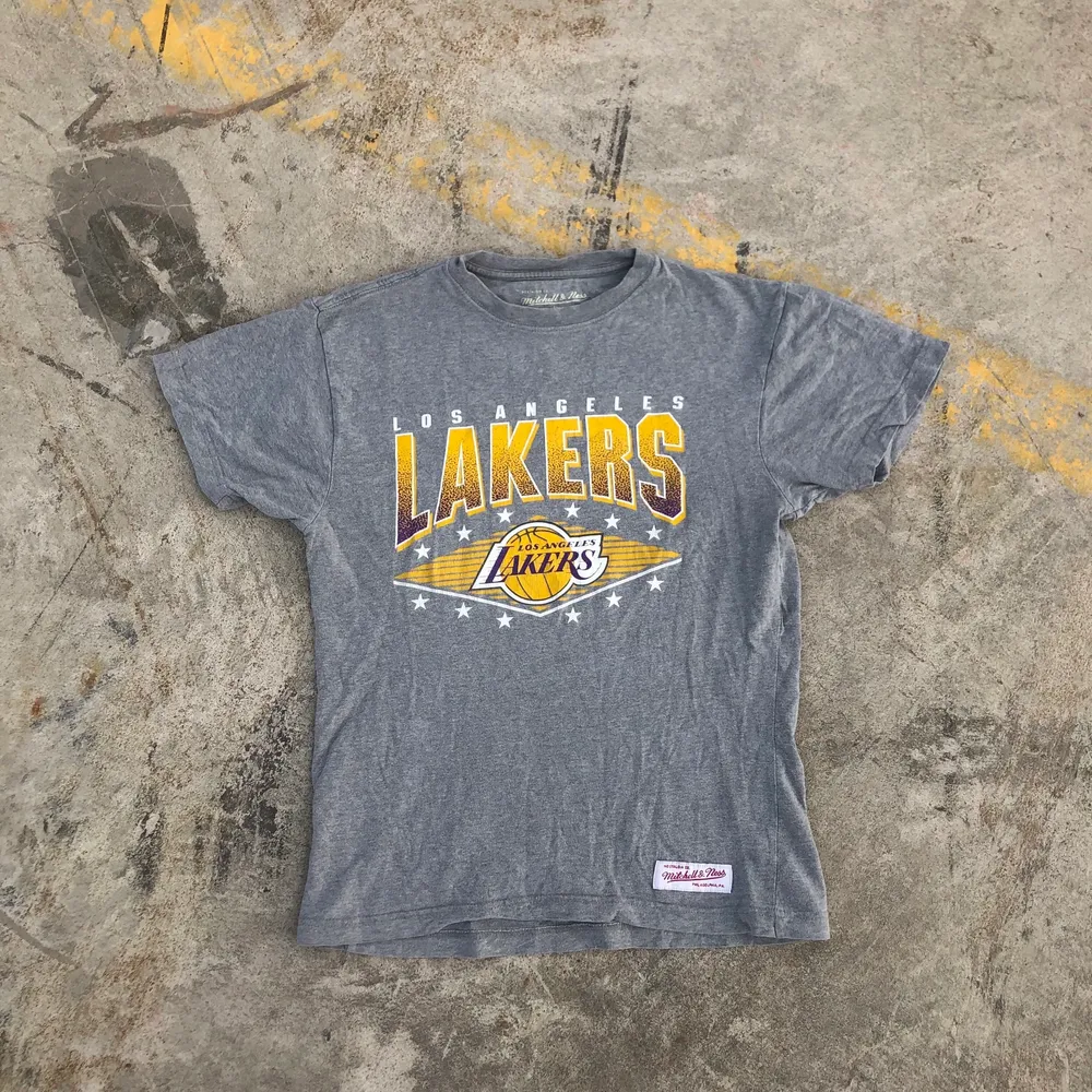 T-shirt producerad av de anrika Mitchell & Ness åt Nba-laget Los Angeles Lakers. Tröjan är i grymt skick, trycket är dock lite slitet men det är inget som stör helheten av tröjan. riktigt najs t-shirt till sommaren. Tröjan är S men skulle snarare säga att det är en Xs. Det är bara att skriva om du undrar något! 💛💜. T-shirts.