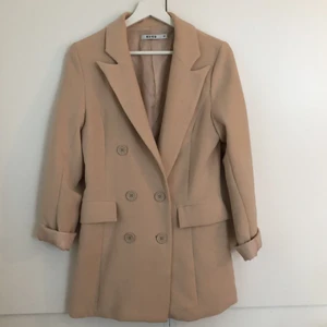 Nakd kavaj strl 34 - Beige kavaj från NAKD. Fint skick, ändats använd ett fåtal gånger. Mjukt och bekvämt material och fin passform!