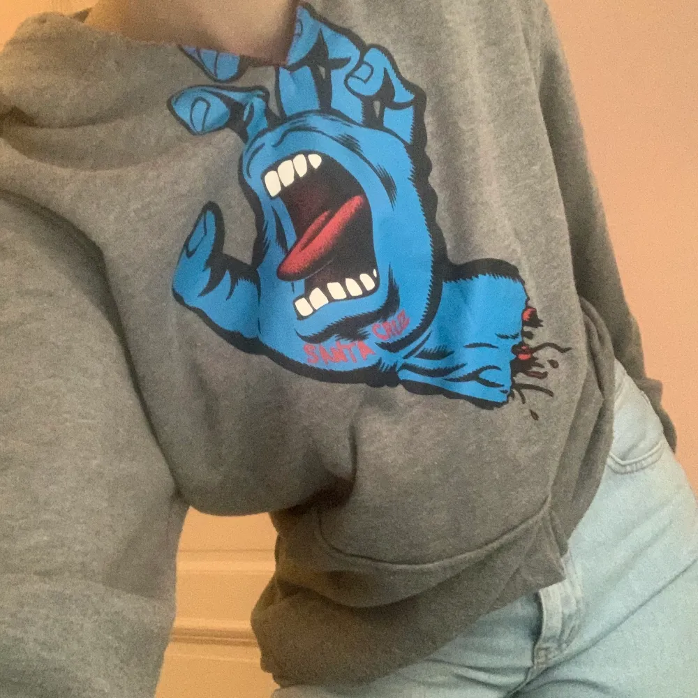 Grå santa cruz hoodie med tryck💕 den har en slits vid bröskorgen men tycker bara att det är en snygg detalj! Storlek S. Säljer för 150kr + frakt!!. Hoodies.