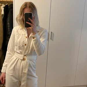 Denim jumpsuit - Vit jumpsuit i denim med tillhörande skärp. Använd nån gång men som i nyskick. Väldig mjuk och skönt material. Fina guldiga detaljer. Säljer för jag tycker den är lite kort i benen för min smak, jag är 170 lång. Strl 38, jag har normalt 36 men skulle säga att den passar bra både 36-38 då skärpet i midjan avgör passformen. Kan mötas upp annars står köparen för frakten 