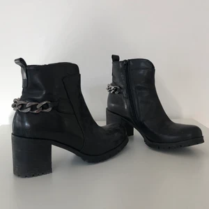 Svarta klackskor med kedja baktill  - Svarta klackskor med en silvrig kedja baktill. Storlek 38. 