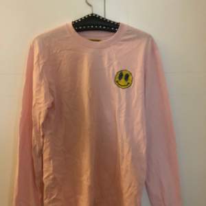 En ljusrosa långärmad tröja från Urban Outfitters med smiley tryck!💘fraktpris diskuteras:)