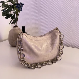 Handväska  - Väska från Nelly i beige med silverfärgat axelband. Gullig men kommer inte till användning. Som i nyskick 🦋