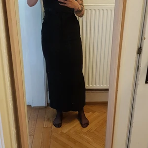Svart långkjol 90's style - Svart långkjol från Hennes (gamla H&M) mycket snygg med flera fickor med dragkedja och slits bak. Smal passform, sitter högt i midjan. 