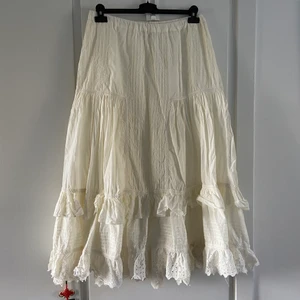 Cottage core kjol - En underbar vit fladdrig sommarkjol 💓⭐️🌸 Maxi-längd och söta volanger med broderier! Perfekt som cottage core stil eller bara vintage, dreamy, hippie-stil! Storlek 42-44 men mer som 40-42 🌺 Jag är 44 med breda höfter och den satt för tight på mig. ✨ Fint begagnat skick, nån liten fläck baktill men det syns inte i allt svall när den är på 🥰🍇🌤 Så snygg till små sandaler och en croptop! 