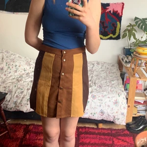 Kjol med knappar - En kjol i flera nyanser av brunt. Har knappar på framsidan, och går att knäppa upp hela vägen. Kort kjol, utan att vara för kort! 