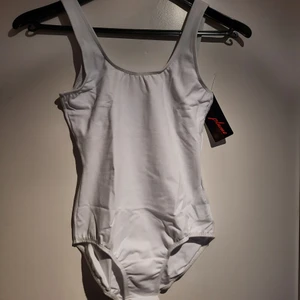 Helt ny vit Balettdräkt - Jättefin vit balettdräkt som aldrig använts. Den är mycket stretchig och i originalförpackning med lappen kvar. Material: 88% Cotton och 12% Spandex. Den har en inbyggd BH, vilket syns på den tredje bilden, där dräkten är vänd ut och in. Jag säljer en likadan dräkt i storlek S, så in och titta, ifall denna skulle vara för stor. 😊 Skriv till mig vid funderingar eller för fler bilder💕