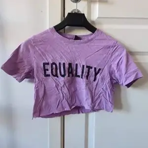 Croppad lila t-shirt med text ” Equality“ storlek XS