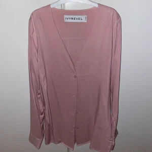 IVYREVEL SKJORTA (One-size) - Jättefin skjorta från IVYREVEL i strl one-size. Kan stylas på flera olika sätt då man kan välja att knyta den eller knäppa alla knappar. Skjortan är V-ringad och har slitsar på båda sidorna. Använd några gånger men fortfarande i mycket bra skick.  Pris:100 kr eller högsta bud.  OBS: köparen står för fraktavgiften och köparen bestämmer själv om paketet ska vara spårbart eller icke spårbart.