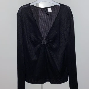 Ribbad tröja med detaljer - Svart ribbad tröja i strl M (passar som en S) från H&M (divided by HM). Tröjan är V-ringad och har även en metallring mellan brösten som en väldigt fin detalj. Använd fåtal gånger, bra skick!  Pris: 75kr (priset kan diskuteras)  OBS: köparen står för fraktavgiften och köparen bestämmer själv om paketet ska vara spårbart eller icke spårbart.
