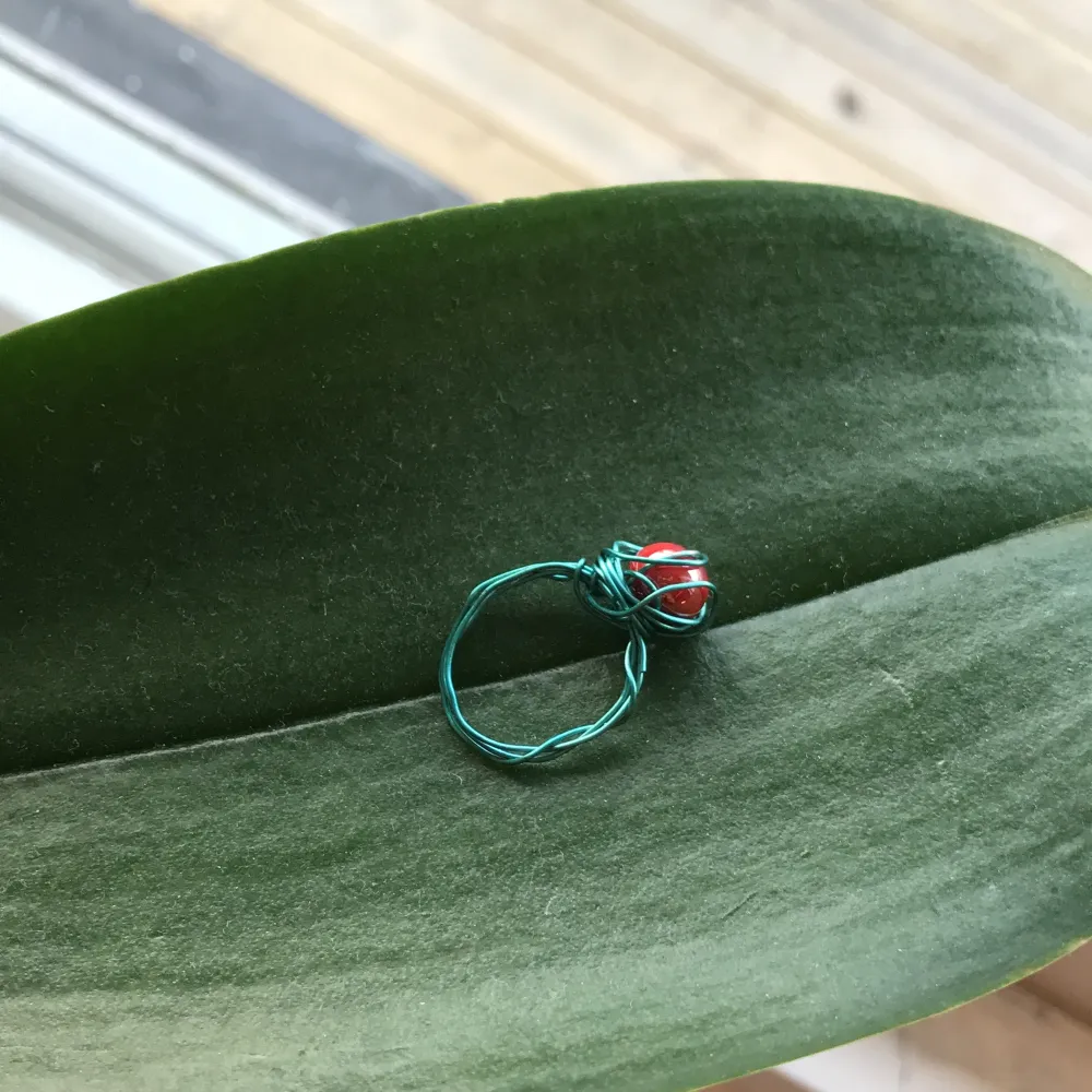 Väldigt fin ring av blå ståltråd och en röd pärla. . Accessoarer.