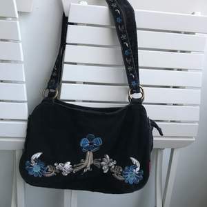 Snygg svart/mörkblå handväska i manchester. Med broderade blommor på väska och band.