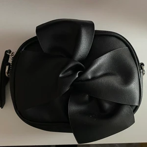 Väska  - handväska med rosett, ingår band till väskan. Två fack med rymligt utrymme och länder inspirerad material. Väskan är i fint skick💕 köparn står för frakten 