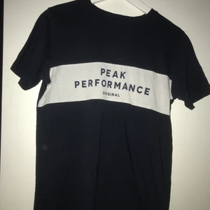Peak Performance t-shirt strl. XS/S - En blå Peak Performance t-shirt i storlek XS/S. Stort vitt och blått märke på bröstet. 