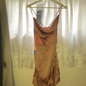Boohoo silkesklänning strl 36/S/XS - Roséguld/smutsrosa klänning med korsade band i ryggen. Relativt nyskick, säljer pga den är för liten för mig, inga hål eller brista sömmar. Pösig fram vid bysten och ganska kort, jättefin <3