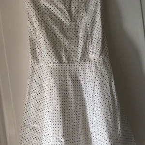 Prickig klänning - Säljer denna söta vit/svart-prickiga bandeauklänningen. Den är så fin, sitter tight på överkroppen och går ut fint vid ”kjolen” så den hänger ”flowigt” typ. Har tyvärr ingen bild på hur den ligger på eftersom den är alldeles för liten på mig:( Hittar tyvärr ingen etikett i heller men den passar ungefär xs/s!💗
