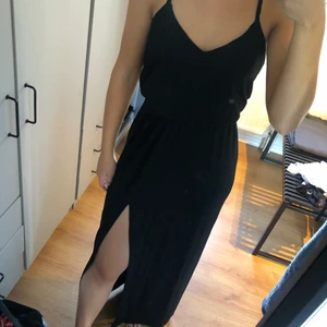 Lång klänning - En svart långklänning med korsade band i ryggen, den har även slitta vid benen