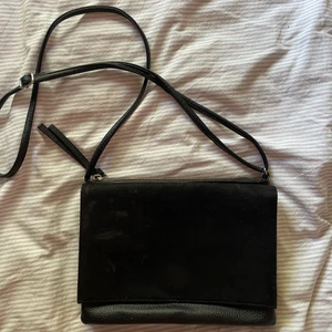 Svart axelväska  - Svart axelväska med två fack, ett fack som sängs med en magnet och ett fack som sängs med en dragkedja. Väskan är i bra skick och materialet är mocka och skitimitation👜🖤🥰                                                           Köp direkt för: 149kr