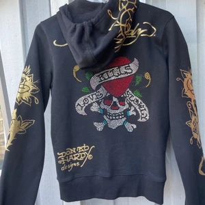Ed Hardy Ziphoodie WOMEN - En snygg ziphoodie från Ed Hardy, hängde bara i garderoben. Ej använd. Lite liten i storleken. Rhinestones på ryggen. I fint skick, precis som ny 👌 SÄLJES FORTFARANDE KONTAKTA MIG VID SNABBT KÖP 750 KR