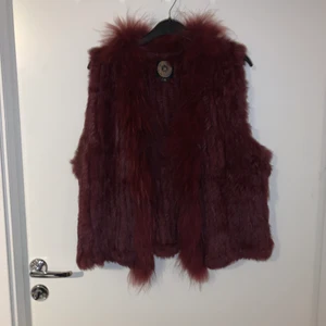 Väst i äkta päls från Red One Original - Säljer min oanvända pälsväst från märket Red one original. Köptes för 2000 kr.  Pälsen kommer från mink och är vinröd.  Ingen värmande väst utan används inomhus.  Storlek 40 men passar även större eller mindre storlekar beroende på vilken stil man är ute efter.  Säljes för 500 Priset kan diskuteras vid snabb affär! 😊