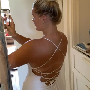 Bikbok klänning med snörning i ryggen - Vit Klänning med snörning i rygg men även en slits nedtill. Passar nästan alla olika storlekar och består av ett otroligt skönt och strechigt material. Klänningen består av ett dubbelvikt tyg vilket gör att klänningen aldrig blir genomskinlig oavsett tex färg på trosor