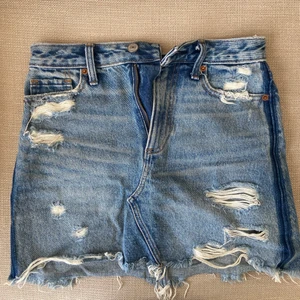 Jeanskjol med slitningar  - Jeanskjol med slitningar i bra skick från Abercrombie & Fitch. Säljer eftersom kjolen är lite liten på mig, därav ingen bild med kjolen på! Vet inte exakta storleken men skulle gissa på Xs!