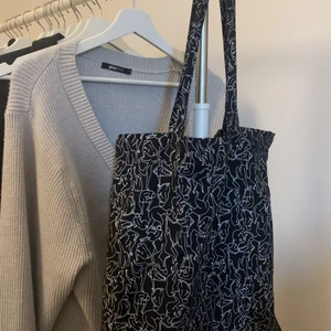 Tygpåse med tryck - Svart tygpåse med vitt tryck köpt på Monki. I ny skick eftersom den är endast använd enstaka gånger. Köpare står för frakten!!!