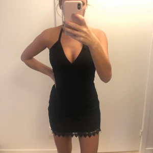 Halterneck klänning - En svart halterneck klänning i spets som man knyter i nacken + dragkedja i ryggen. Klänningen är köpt utomlands och bara använd 1 gång. 